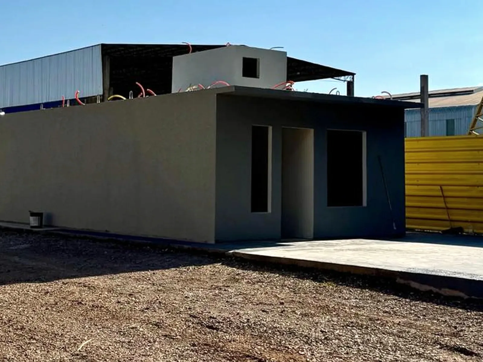 Módulo de casa pré-fabricada pronto e pintado, com vãos de porta e janelas, no pátio da fábrica