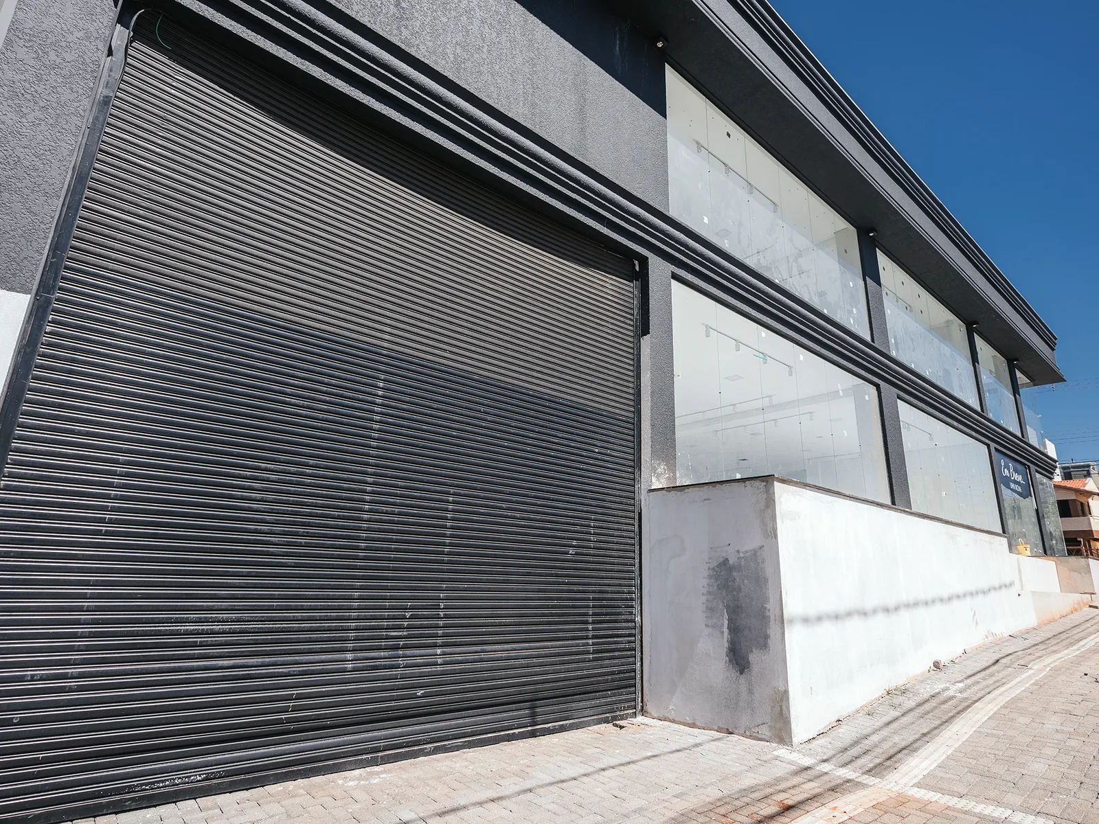 Centro comercial pré-moldado concluído em esquina, com fechamento metálico