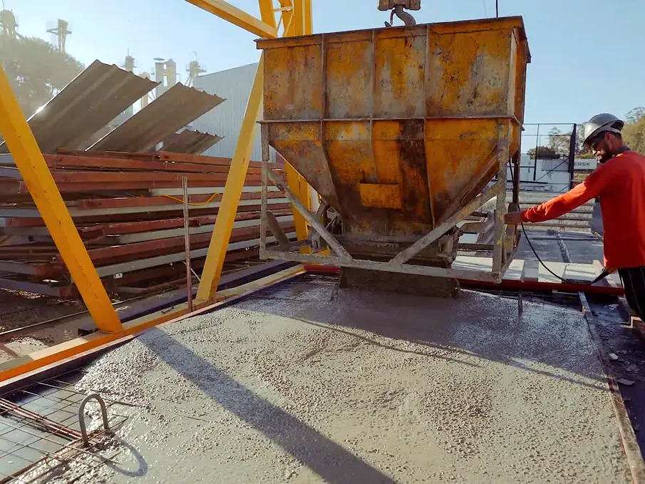Concretagem de peça pré-moldada com caçamba na pista de produção